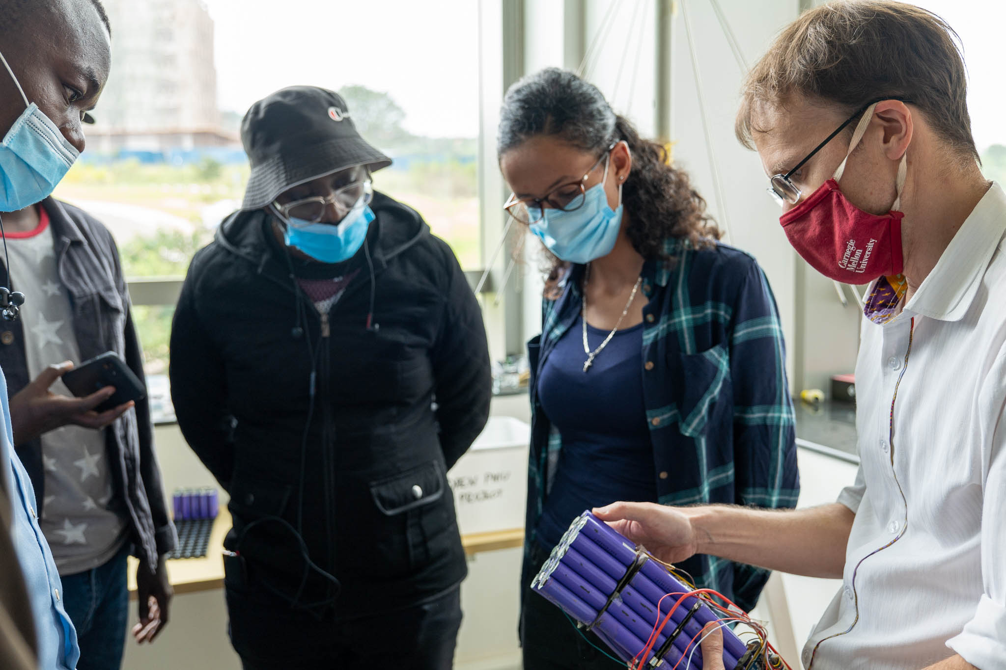 Professor Rawn with students looking at a battery