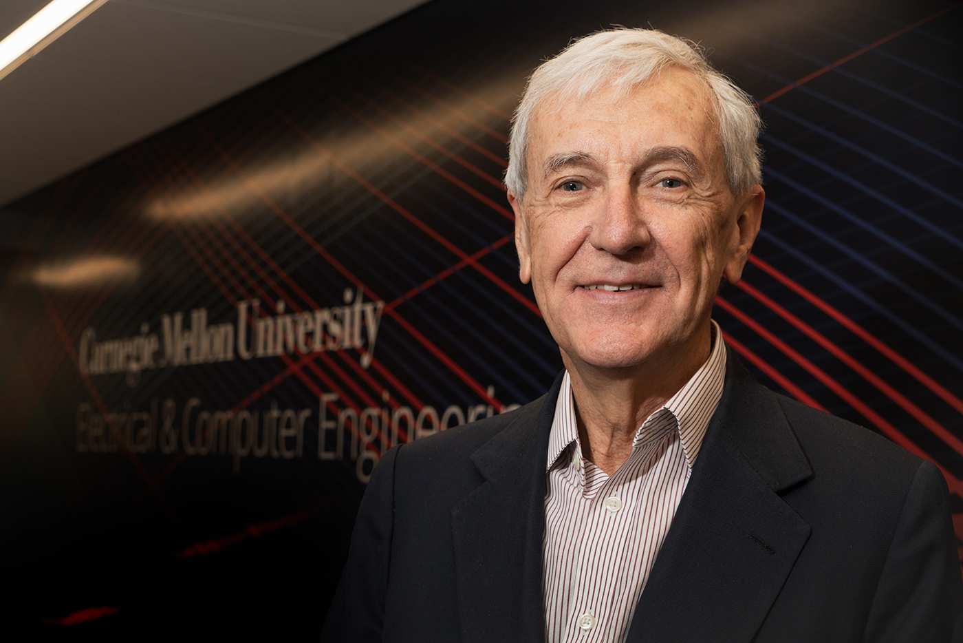 Jose in front of a wall with the CMU logo