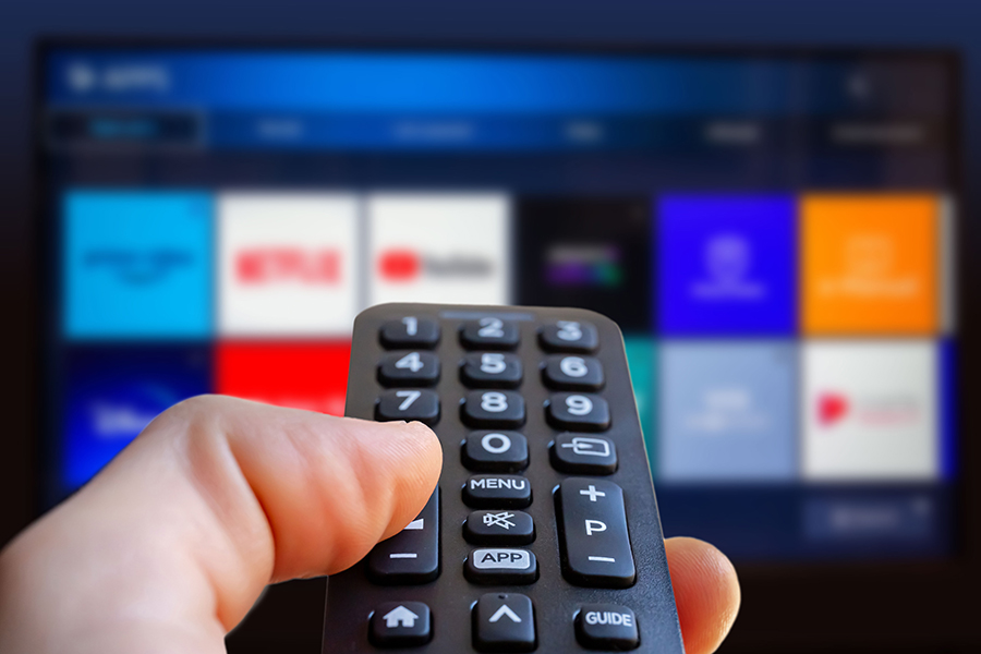 Man holding a remote who is about to choose a streaming service to watch